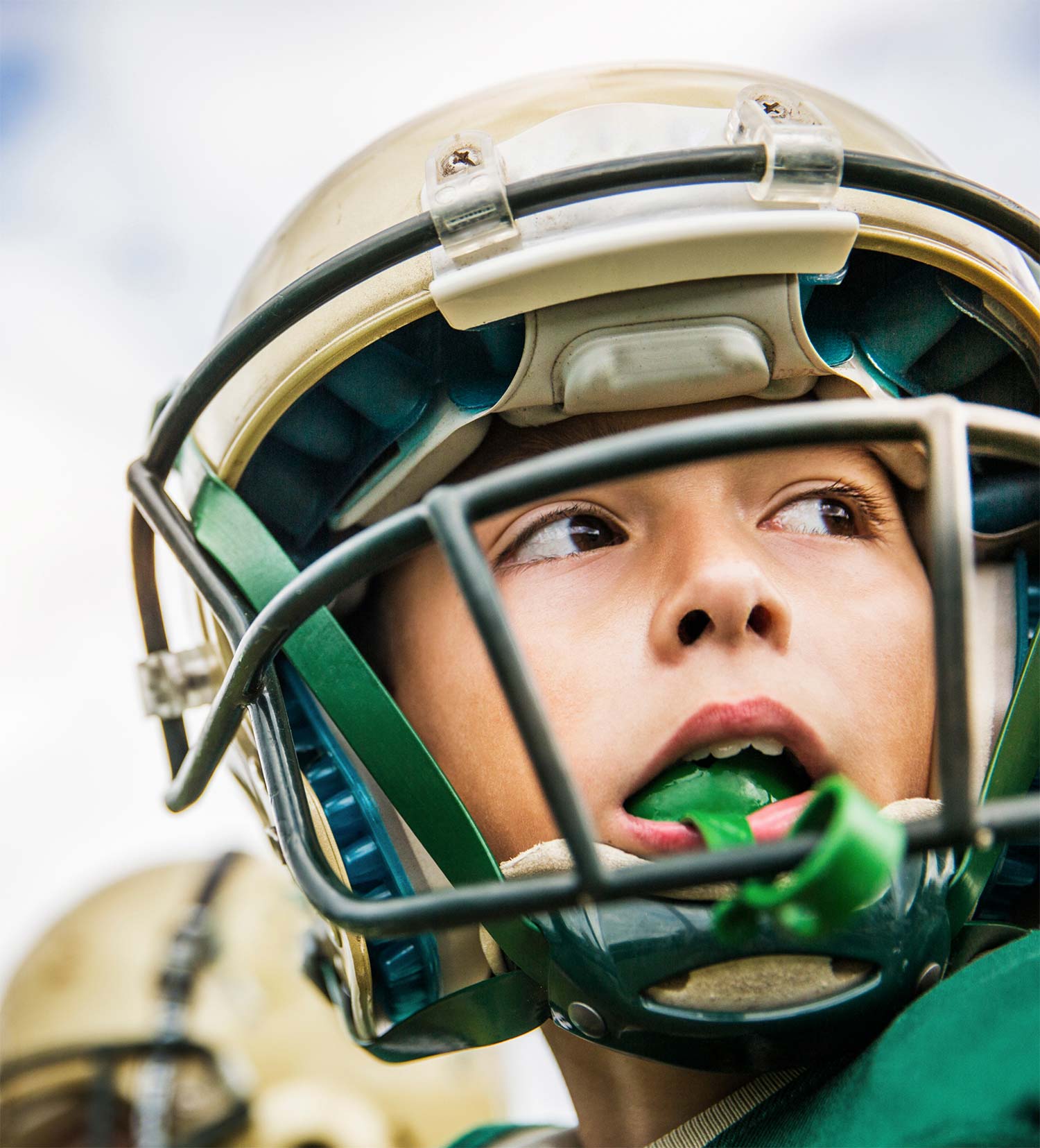 Child playing football with mouthguard in his mouth.